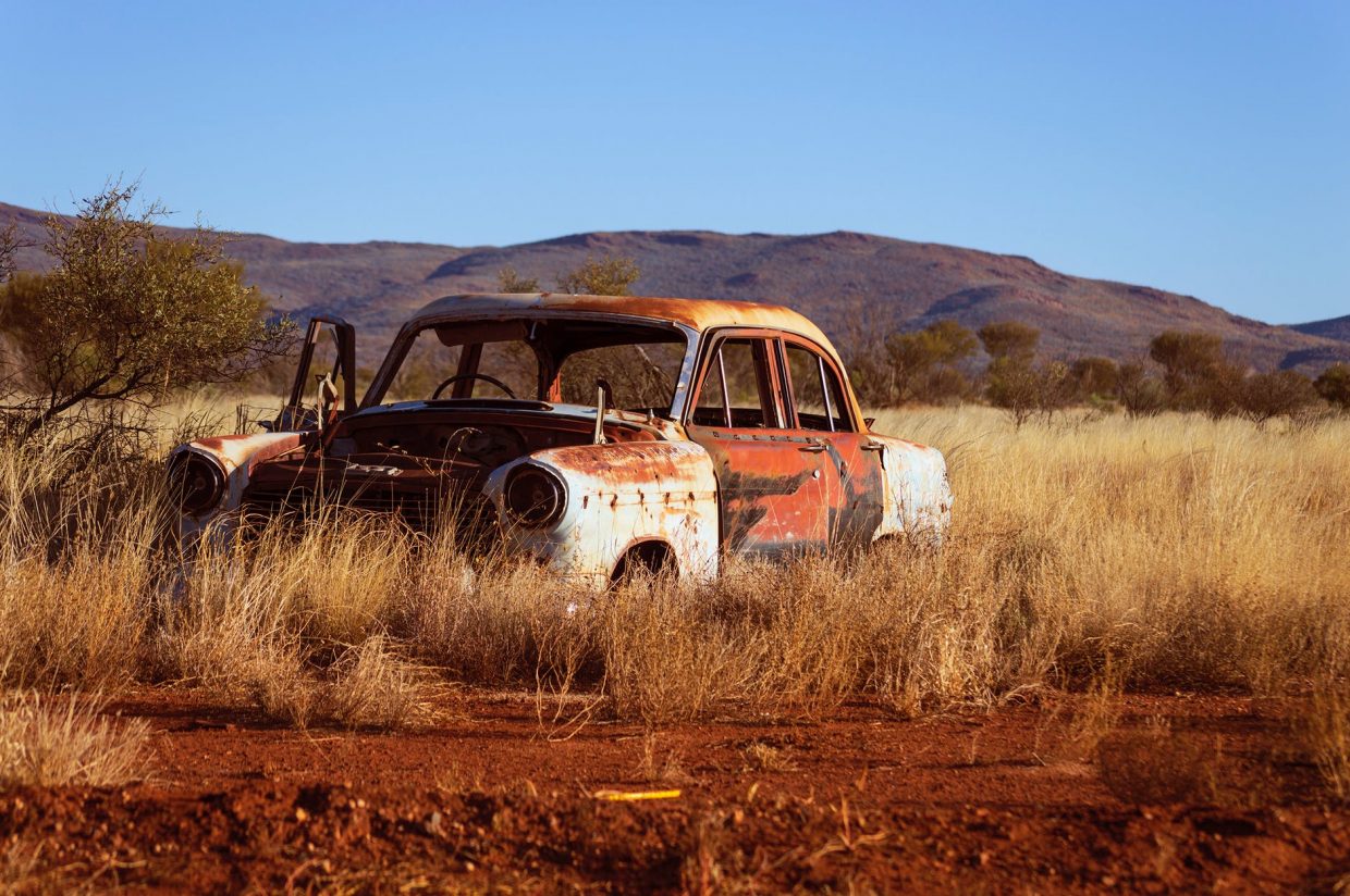 photo of corroded vintage white and red sedan on brown grass