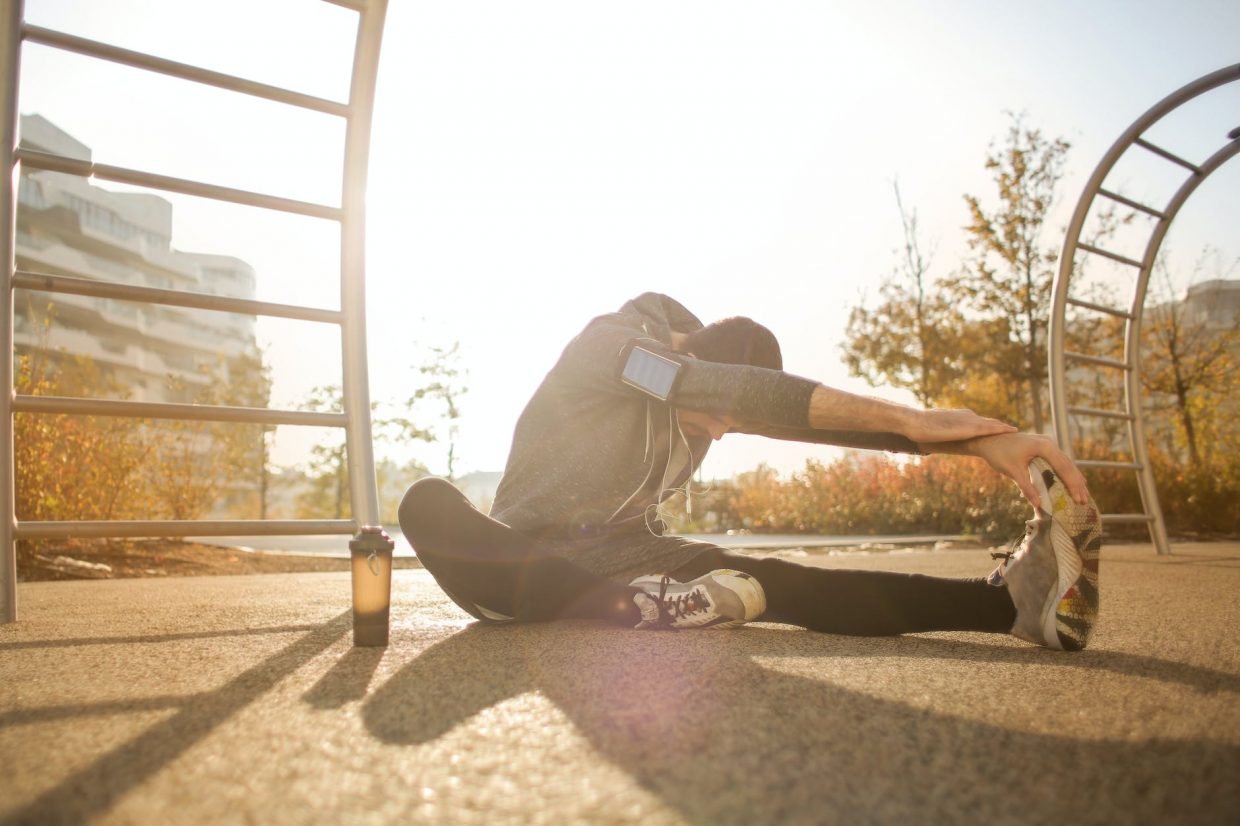 flexible sportsman stretching on sports ground